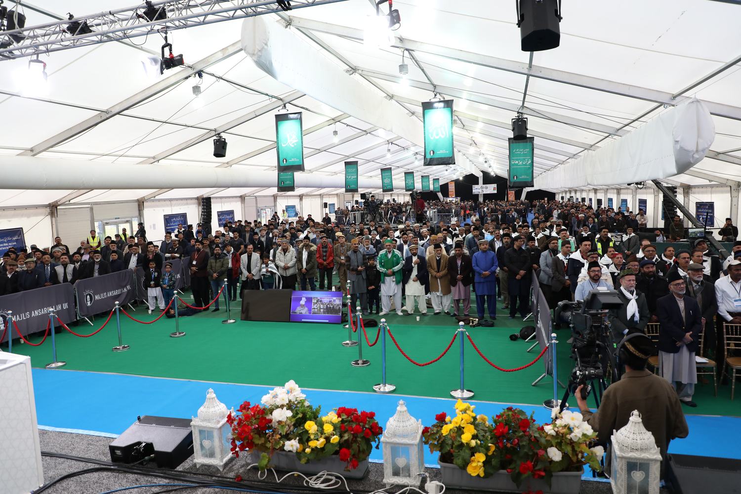 A large congregation standing in the main marquee at the 2025 Ijtema, seen from behind the stage