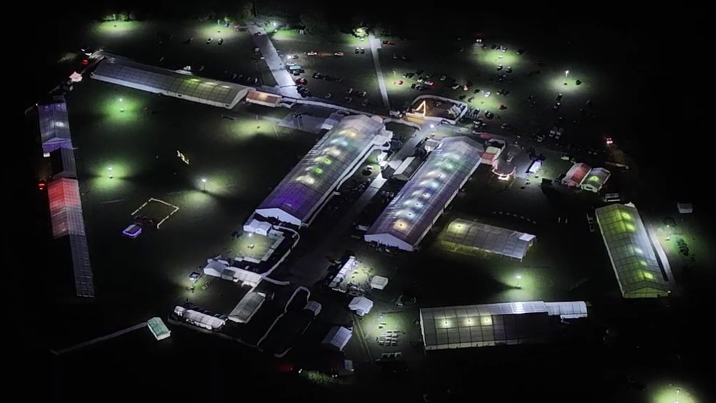 The Ijtema site at Puttenham seen from the air at night, the main marquees lit from within and the accommodation marquees, roads and parking areas picked out by floodlights